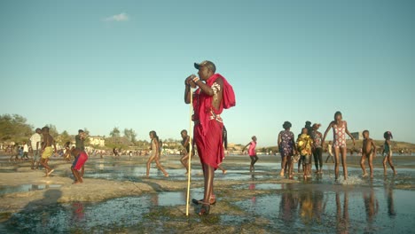 Guerrero-Masai-Rodeado-De-Niños-En-La-Playa-En-La-Ciudad-De-Watamu,-Kenia