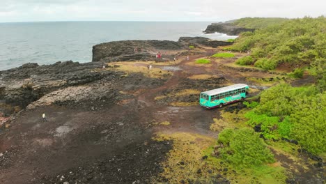 Turquoise-colored-bus-parked-on-a-cliff-as-tourists-see-the-pont-naturel-in-Mauritius