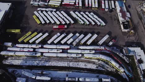 Aerial-view-of-public-transportations-parking-lot-with-buses-and-trams-covered-with-snow