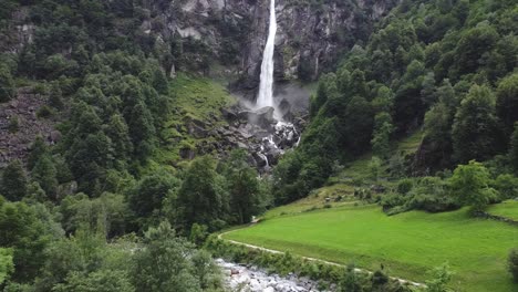 Heaven-on-Earth:-waterfall-in-deep-valley-of-Switzerland-mountains,-aerial-fly-back-view