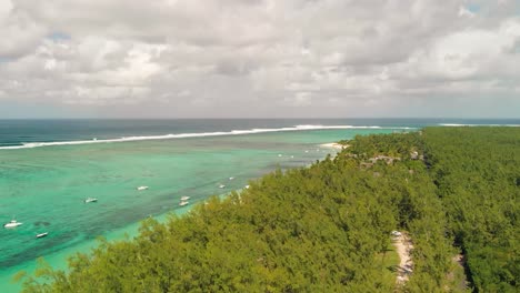 Aerial-view-of-trees-under-cloud-cover-at-Le-Morne-beach-with-parked-boats