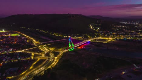 Aerial-Hyperlapse-Above-Temuco-City-at-Sunset-Nighttime-Chile,-Roundabout,-Cable-Bridge-above-Cautin-River,-Hill-Houses-at-Andean-Valley-Araucaria-Region