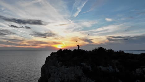 Cinematic-reveal-of-person-standing-on-ocean-cliff-edge-at-sunset-in-Spain