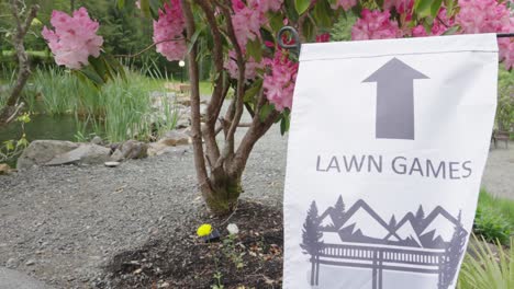 Lawn-games-sign-in-a-farm-with-a-pink-azalea-tree