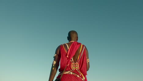 Back-View-Of-An-Indigenous-Maasai-Warrior-In-Red-Traditional-Clothes-And-Tribal-Jewelry-In-Watamu,-Kenya