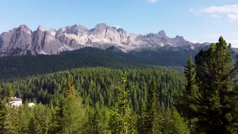 Dolomites-mountain-range-in-distance-and-close-by-fly-to-forest-tree-tops