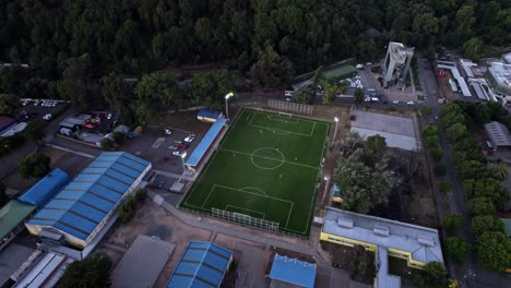 Aerial-Drone-Above-Soccer-Match,-Field-in-Temuco-City,-Chile,-Green-Grass-Football-Pitch-near-Exotic-Forestry-Landscape