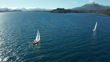 AERIAL---Two-sailboats-on-Correntoso-Lake,-Neuquen,-Argentina,-tracking-spinning-shot