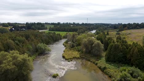 Muddy-water-of-river-flowing-through-Ontario,-aerial-drone-view