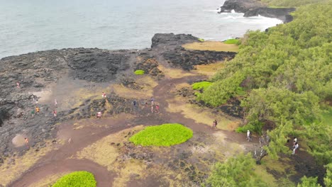 Group-of-people-walking-to-the-pont-naturel-on-a-cliff-of-volcanic-rocks-in-Mauritius
