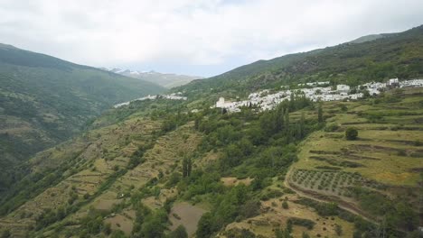Aerial-ascending-view-of-the-valley-of-Poqueira-with-the-villages-of-Bubion-and-Capileira-with-Sierra-Nevada-behind
