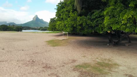 Beach-front-at-Flic-En-Flac-with-a-mounted-sign-under-trees-and-mountains-in-the-background