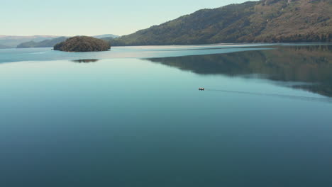 AERIAL---Beautiful-reflection-and-boat-on-Hermoso-Lake,-Neuquen,-Argentina,-forward