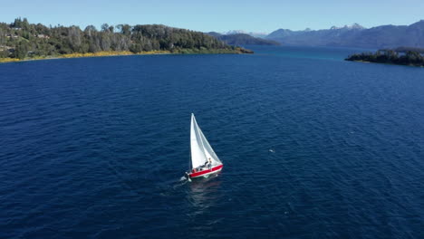 AERIAL---Sailboat-on-Correntoso-Lake,-Neuquen,-Argentina,-spinning-shot