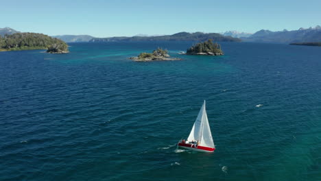 AERIAL---Two-sailboats-on-Correntoso-Lake,-Neuquen,-Argentina,-tracking-shot-reverse