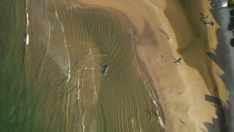 Aerial-time-lapse-top-down-shot-of-kayaks-arriving-shore-of-sandy-beach-in-Uruguay
