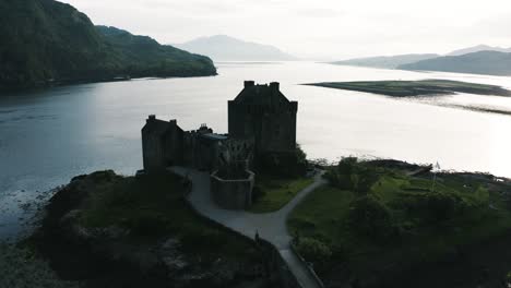 Orbiting-aerial-view-of-the-Eilean-Donan-Castle's-silhouette-on-a-bright-day