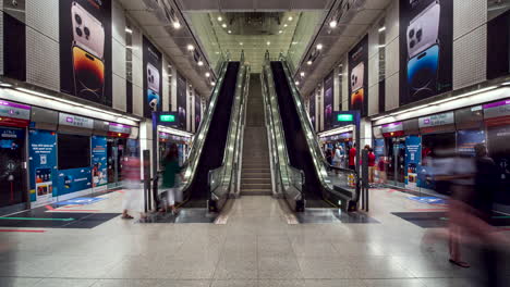 People-moving-up,-down-escalators-through-Dhoby-Ghaut-MRT-Station,-Singapore