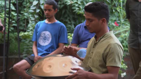 Young-handsome-man-drumming-on-his-tabor-or-singing-bowl,-doing-a-performance