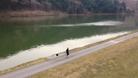 drone-footage-of-a-man-walking-next-to-a-river-pans-to-the-right