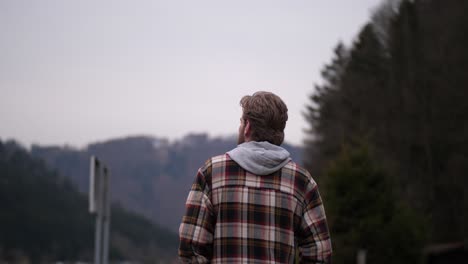 A-man-dressed-in-a-plaid-sweater-is-shown-from-behind-taking-a-walk
