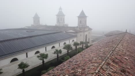 Drone-flying-over-roof-of-Chateau-Cos-d'Estournel-winery-on-misty-day,-Bordeaux-region-of-France