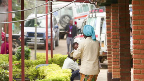 Slow-motion-shot-of-woman-as-she-walks-into-frame-holding-a-young-Child-at-a-rural-hospital-in-Rwanda
