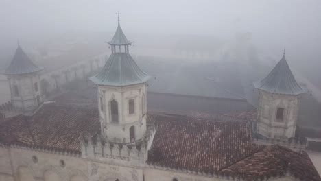 Drone-flying-over-Chateau-Cos-d'Estournel-winery-on-foggy-day,-Bordeaux-region-of-France