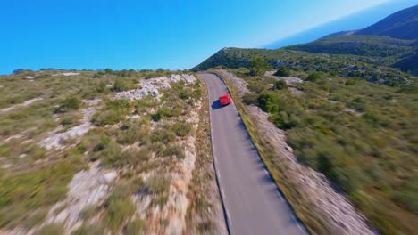 Picturesque-aerial-view-following-a-red-Ferrari-as-it-travels-along-a-scenic-mountain-roadway