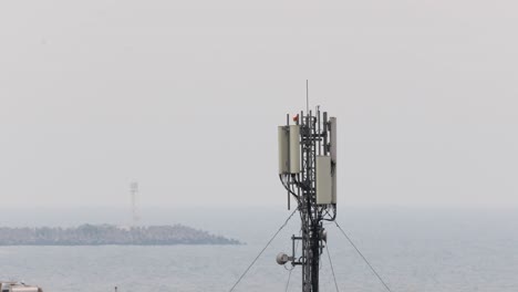 Cellular-Network-Tower-Antenna-Standing-On-The-Sea-Coast-With-Seascape-In-Fog-Backdrop