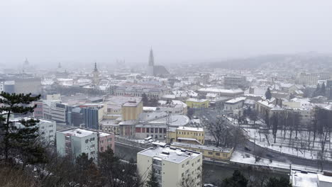 Cluj-Napoca-City-wide-view,-seen-on-a-overcast-and-gloomy-day-at-winter-surrounded-by-fog-and-snow
