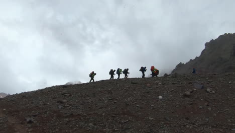 Group-of-people-hiking-up-a-ridge-in-a-snow-shower,-just-above-Plaza-Argentina-on-the-ascent-to-Aconcagua
