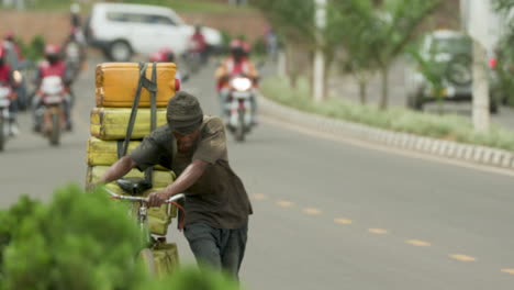 El-Hombre-Empuja-La-Bicicleta-Al-Costado-De-La-Carretera-En-Kigali,-Ruanda