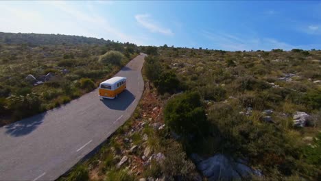 FPV-drone-chasing-a-vintage-VW-bus-on-a-beautiful-sunny-day-in-the-hills-of-Catalonia
