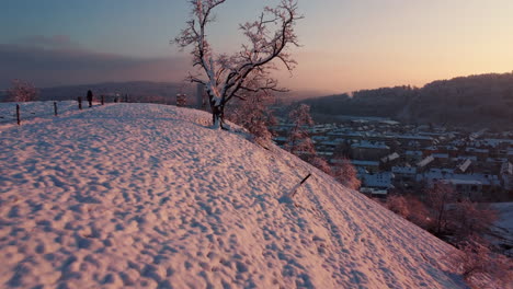 Flying-over-the-edge-of-a-snowy-hill-during-a-red-winter-sunset