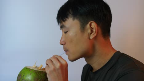 Nahaufnahme-Eines-Südostasiatischen-Jungen-Mannes,-Der-In-Zeitlupe-Durch-Einen-Kokosnussstroh-Trinkt