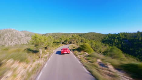 Epic-FPV-aerial-following-a-Red-Ferrari-driving-through-the-picturesque-hills-of-Catalonia,-Spain