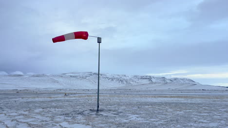 Calcetín-De-Viento-Moviéndose-En-El-Viento-En-Un-Aeropuerto-Congelado-En-Islandia-Con-El-Fondo-En-Un-Paisaje-Cubierto-De-Nieve