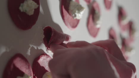 Forming-homemade-fresh-beetroot-tortellini-pasta-by-hand-4K-Close-Up-Vertical