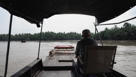 Mekong-Delta,-Vietnam,-December-10-2022---Boat-ride-on-the-Mekong-River,-Saigon:-Man-driving-upstream-through-coconut-palms