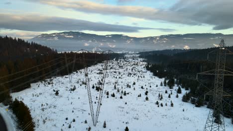 Close-Drone-Shot-of-Powerlines-Running-Through-Snowy-Winter-Landscape