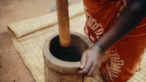 Schwarzafrikanische-Dame-Mahlt-Kaffeebohnen,-Um-Gemahlenen-Kaffee-Mit-Holzmörser-Und-Stößel-Zuzubereiten-–-Traditionelle-Ugandische-Methode