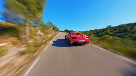 Aerial-view-flying-fast-behind-a-red-Ferrari-driving-along-a-scenic-country-road