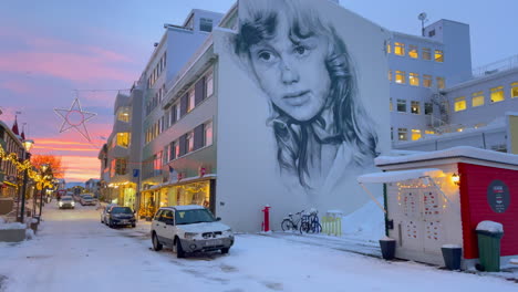 Beautiful-mural-of-a-girl-on-an-apartment-complex-in-a-cozy-street-lit-with-Christmas-lights-in-Akureyri-in-Iceland-in-winter-time
