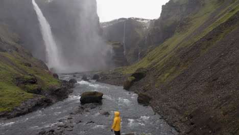 Drone-pullback-to-reveal-one-person-standing-on-a-rock,-near-Haifoss-waterfall-in-Iceland