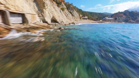 FPV-drone-flying-quickly-along-a-beach-past-boathouses-on-the-picturesque-coast-of-Spain