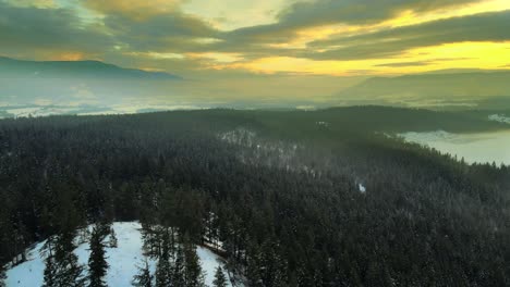 Winter-Sunset-over-the-Evergreen-Forests-near-Enderby,-BC---Drone-Pullback-Shot