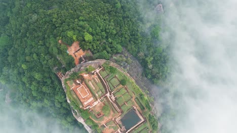 Aerial-video-over-Lion's-Rock-in-Sigiriya-,-historical-mountain-with-buildings-above-the-clouds