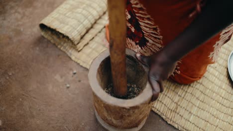 Coffee-beans-manually-pounded-with-wooden-pestle-and-mortar-by-African-woman