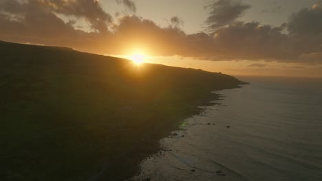 Bright-sunlight-peaking-above-horizon-during-sunset-at-The-Catlins,-aerial